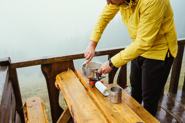 Male tourist in casual clothes preparing to eat at a table on the terrace of a country house in the mountains.