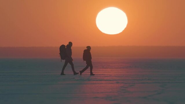 The two backpackers walking through the icy snow field
