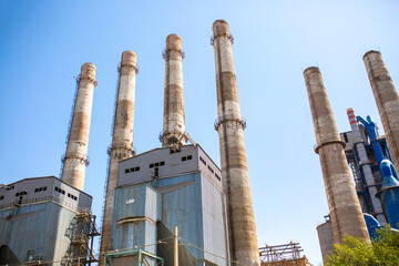 Fototapeta premium Cement factory. Pipes and compressors, equipment, metalurgy. Modern technologies work at a cement plant. Technological work on the production of cement. Working atmosphere with copy space.