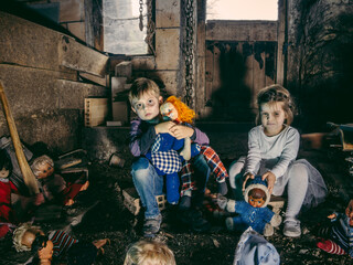 Creepy young children sitting with old dolls in a barn