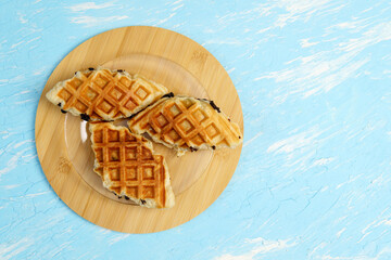 Croffle or Croisant waffle dessert, a marriage between a croissant and a waffle iron. Topview. Blue background