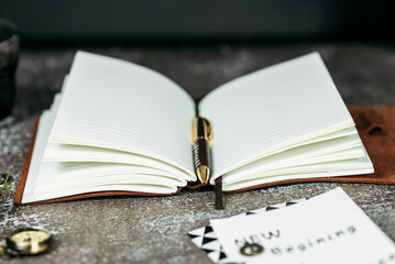 Notebook in a brown leather cover on a black background office style stationery pen clock, leather notebook and fountain pen on a black background. Business concept.