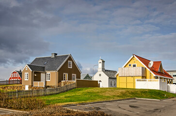 Fototapeta na wymiar Stykkisholmur, Iceland, May 3, 2022: traditional houses and church in the heart of town, illuminated by the evening sun