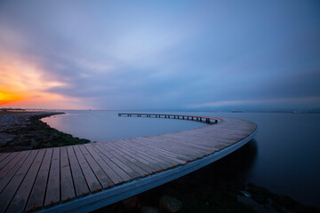 The pier like a boomerang at sunrise was captured with the long exposure technique.