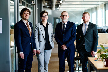 Portrait of successful business team in formal wear looking at camera while standing at office