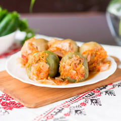 Stuffed with rice and meat green and yellow pepper stew on a wooden plank on an embroidered Ukrainian-style article
