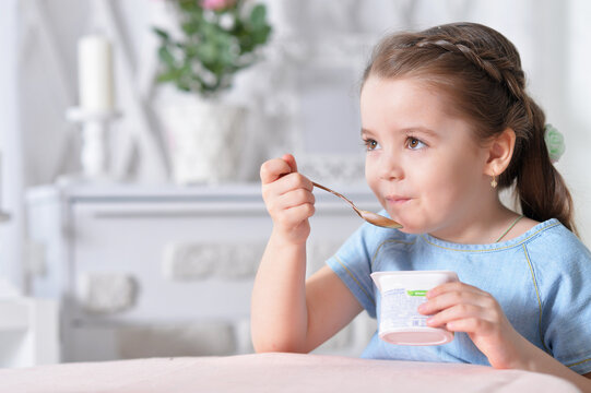 Portrait of cute little girl eating delicious yogurt