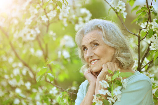 Beautiful senior woman posing near blooming tree