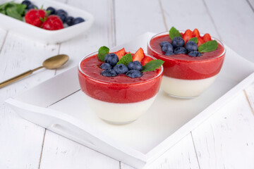 Fruit jelly dessert or panna cotta with fresh strawberries and blueberries, on white background