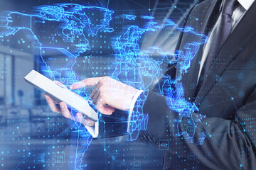 Close up of businessman using tablet with glowing blue map hud screen and digital data concept on blurry office interior background. Info, news and planet. Double exposure.