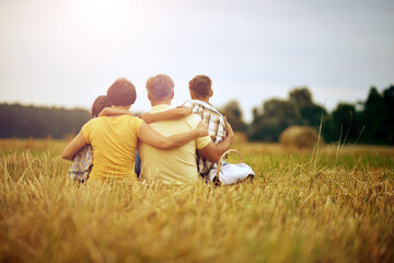 Family sitting on wheat field in sunny day