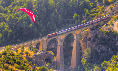 Paraglider flies in the sky - Aerial view of a train moving on the Varda railway bridge
