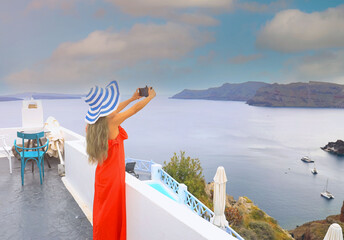 Back view of young tourist woman in red dress using smartphone take picture at View of blue church...