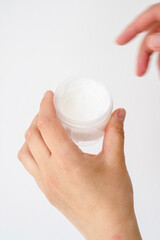Skin care product. Female hand holding a face cream jar on bright background. Beauty skin care product