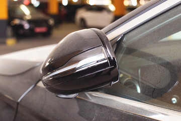Modern folding car mirror with turn signal. Black car, close-up. - obrazy, fototapety, plakaty