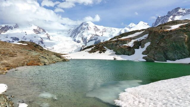 Majestic alpine landscape, extreme hiking in Swiss Alps, sunny glacial lake with snow and mountain peaks in Switzerland, flying above Gornergletcher 