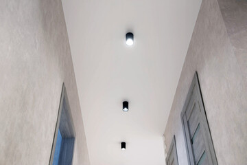 Modern lighting in the hallway on a white stretch ceiling. LED spotlights. Beautiful interior. New technology