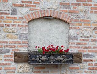 Laid down antique semicircular window in a brick wall with a flowerpot, close-up