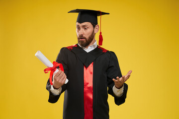 Front view of surprised student looking at diploma, asking. Handsome boy with beard standing,...
