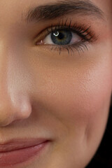 Obraz premium Half a beauty portrait with beautiful fashionable evening make-up, black smoky eyes and extremely long eyelashes. Nude lipstick on the lips. Cosmetology and spa facial skin care