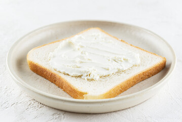 A slice of toast bread with cream cheese in a plate.