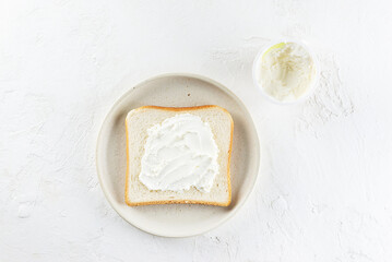 A slice of toast bread with cream cheese in a plate. Horizontal orientation, top view.