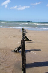 pont en boit enfoncé dans le sable d'une plage