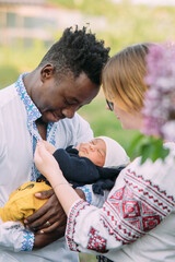 Happy interracial family holds their newborn baby.