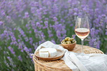 Glass of white wine in a lavender field. Violet flowers on the background.