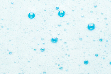Soap foam from shampoo, blue bubbles background.