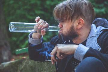 Man drinking vodka and smoking cigarette. Drunk young people. Alcoholism, pain, homelessness,...