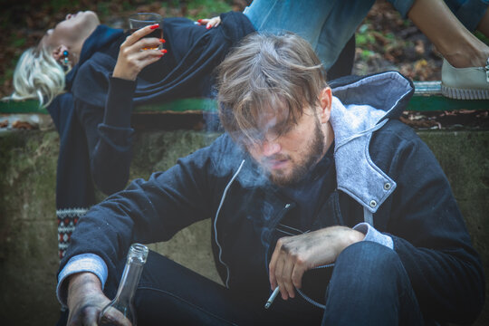 Couple of man and woman drinking vodka.  Drunk young people. Alcoholism, homelessness, social problem of dependence, destructive and antisocial behavior concept.