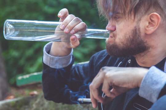 Portrait Of Man Drinking Vodka And Smoking Cigarette. Drunk Young People. Alcoholism, Pain, Homelessness, Destructive And Antisocial Behavior.