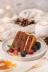 Delicious semi-naked chocolate cake with caramel topping and decorated with blackberries and raspberries. Light background