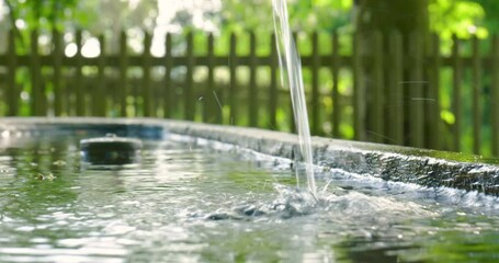 Clean and clear water flowing from a public wooden drinking water fountain in a forest in Switzerland, Europe. Real time close up shot, no people