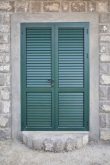 Green door with shutters at the entrance to the house