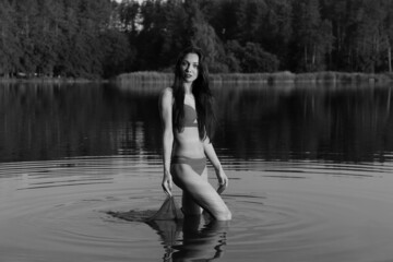 Young long-haired woman in bikini in the lake in black and white
