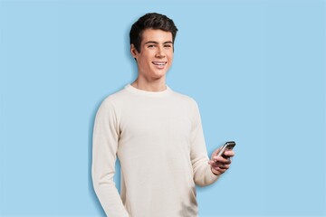 Young man using smartphone on blue background