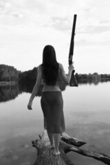 Slender woman with a gun from the back in black and white