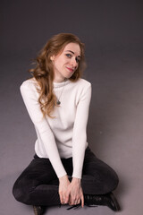 Portrait of playful girl making faces.  Mixed emotions on face: fooling, flirting and smiling. Sitting, black background.