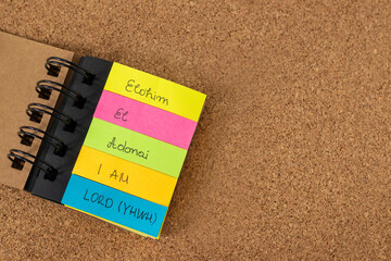Names of God (Elohim, El, Adonai, I AM, LORD-YHWH) written on colorful note stickers on a textured...