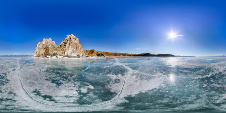 Panorama 360 degree Shaman Rock or Cape Burhan on Olkhon Island in winter, surrounded by the blue ice of Lake Baikal with cracks.