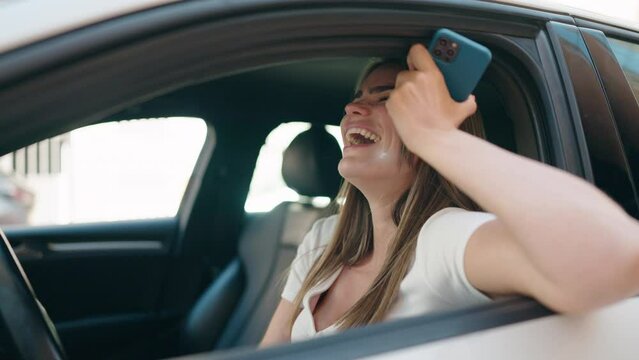 Young woman listening audio message by smartphone sitting on car at street