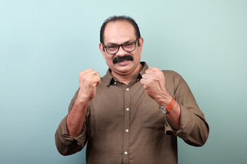 Portrait of a middle aged man of Indian ethnicity shows cheering gesture with both hands