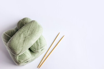 Fototapeta na wymiar Light green yarn threads with knitting needles on a blue background for knitting. Flat lay