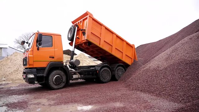 Dump truck (truck) unloads rubble. Lots of rubble at the construction site. Crushed stone at the factory, construction site. Gravel unloading. Rubble.
