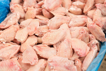 Frozen chicken wings for barbecue at market stall as background with copy space