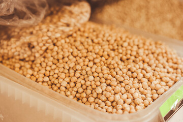 Dried raw chickpeas in plastic container at market stall as background with copy space. Global food...