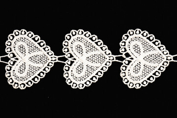 White lace with hearts on black background isolated
