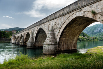 The Ottoman Mehmed Pasa Sokolovic Bridge in Visegrad, Bosnian mountains, reflected in the river...
